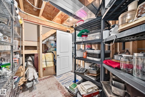 Utility space featuring exposed wood framing, metal shelving, and a paneled white door - 12410 171A Avenue, Edmonton, AB 