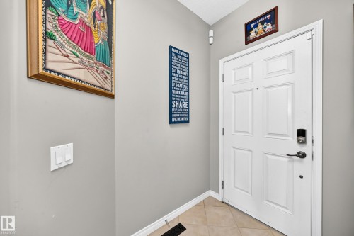 Entryway featuring a paneled door with smart lock hardware, neutral wall paint, and beige tiled flooring - 12410 171A Avenue, Edmonton, AB 