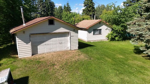 Detached garage with a paneled door, brown shingle roof, and a visible chimney - 5416 51 Avenue, Andrew, AB 