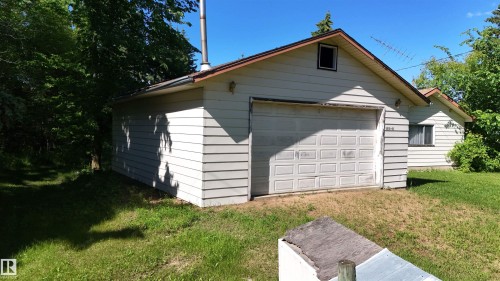 Detached garage with horizontal siding, a pitched roof, and a panel-style garage door - 5416 51 Avenue, Andrew, AB 