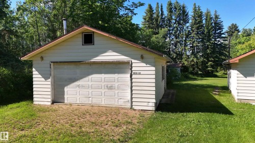 Detached garage structure featuring horizontal siding, an overhead garage door, and a gable roof with a small vent - 5416 51 Avenue, Andrew, AB 