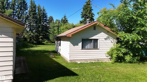 Exterior of a single-story structure featuring horizontal siding, a gabled roof, and a visible window with a screen - 5416 51 Avenue, Andrew, AB 