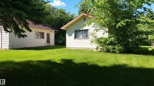 Expansive green lawn with two detached structures featuring horizontal siding and pitched roofs - 5416 51 Avenue, Andrew, AB 