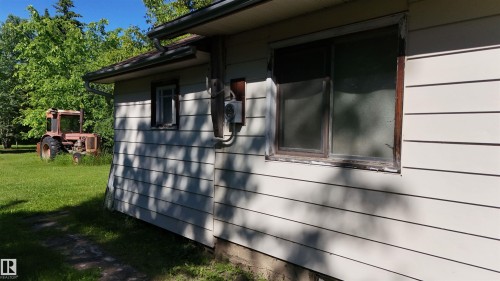 White horizontal siding exterior with a dark roofline and rain gutter system - 5416 51 Avenue, Andrew, AB 