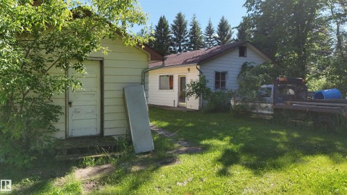 Single-story structure featuring light-colored siding, a brown shingled roof, and a white entry door - 5416 51 Avenue, Andrew, AB 