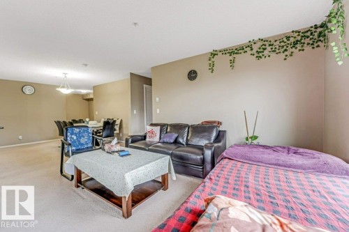 Open-concept living space featuring a dining area with a chandelier, neutral wall colors, and light-colored carpeting - 225 111 Watt Common, Edmonton, AB 