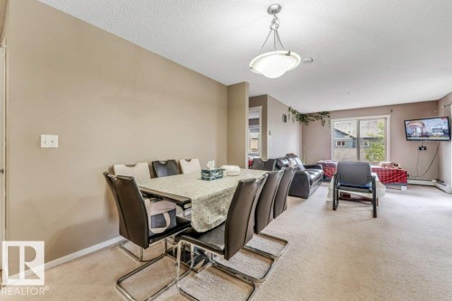 Open-concept living space featuring neutral wall tones, textured ceiling, and carpeting - 225 111 Watt Common, Edmonton, AB 