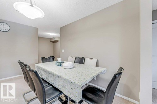Dining area with carpet flooring, neutral painted walls, and a contemporary ceiling light fixture - 225 111 Watt Common, Edmonton, AB 