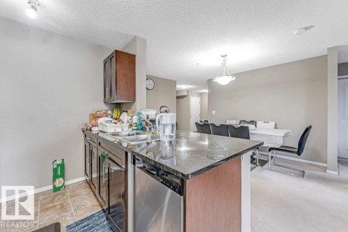 Kitchen with dark granite countertops, stainless steel dishwasher, and wood cabinetry - 225 111 Watt Common, Edmonton, AB 