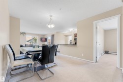 Dining area featuring carpet flooring, a central chandelier, and a pass-through counter to the kitchen - 