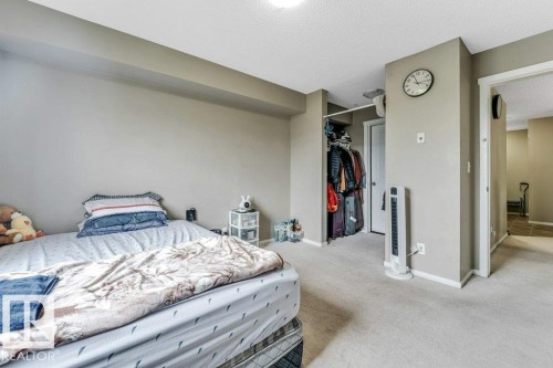 Carpeted room featuring neutral wall tones, an open closet area with hanging rod, and a doorway leading to an additional space - 225 111 Watt Common, Edmonton, AB 