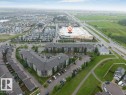 Aerial perspective showcasing the residential buildings with multiple levels, surrounding green spaces, and surface parking areas - 225 111 Watt Common, Edmonton, AB 