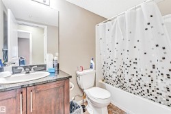 Full bathroom featuring a dark wood-finish vanity with a stone countertop, an undermount sink, and a chrome faucet - 