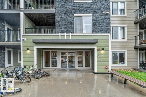 Building exterior featuring an entryway with double glass doors, sconce lighting, and a durable concrete landing - 225 111 Watt Common, Edmonton, AB 