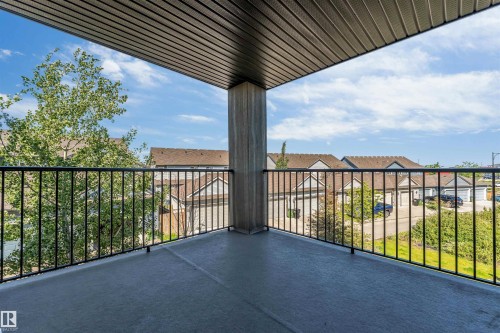 Spacious covered balcony featuring a concrete surface and black metal railings - 225 111 Watt Common, Edmonton, AB 
