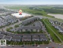 Aerial perspective showcasing a large commercial retail building with extensive parking, multi-story residential buildings, and rows of townhouses - 225 111 Watt Common, Edmonton, AB 