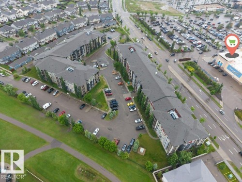 Multi-unit residential buildings featuring dark shingle roofing and exterior siding in shades of gray and brown, complemented by green landscaping - 225 111 Watt Common, Edmonton, AB 
