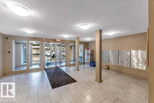 Entry foyer featuring light-toned tile flooring, neutral wall paint, overhead dome lighting, and built-in mailboxes - 225 111 Watt Common, Edmonton, AB 