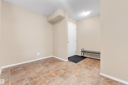 Foyer with tan walls, textured ceiling, and square tile flooring - 