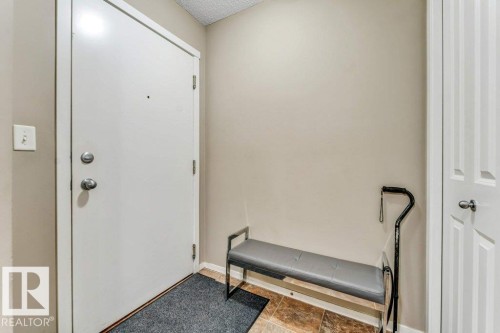 Entryway featuring a white door with brushed metal hardware, neutral wall paint, and a built-in paneled closet - 225 111 Watt Common, Edmonton, AB 