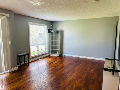 Spacious interior featuring wood-finish flooring, neutral gray wall paint, and white trim - 89 12050 17 Avenue, Edmonton, AB 