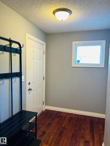 Inviting entryway featuring wood-finish flooring, a paneled door, and a flush-mount ceiling light - 89 12050 17 Avenue, Edmonton, AB 