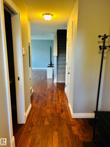 Rich wood-finish flooring extending through the hallway - 89 12050 17 Avenue, Edmonton, AB 
