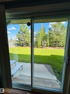 Sliding glass door opening onto a concrete patio with wood-finish steps - 