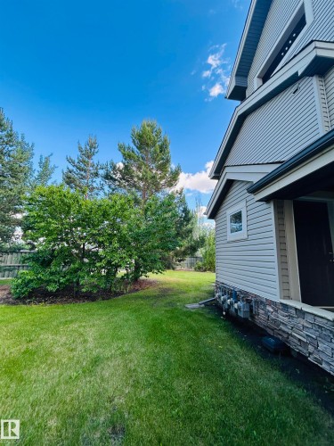 Expansive grassy yard with mature trees and a wood fence - 89 12050 17 Avenue, Edmonton, AB 