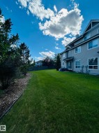 Expansive green lawn bordering a multi-story residence with horizontal siding - 