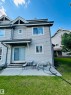 Rear exterior featuring light-toned siding and multiple windows - 89 12050 17 Avenue, Edmonton, AB 