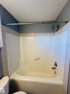 White bathtub and shower combination unit featuring a chrome showerhead and faucet - 