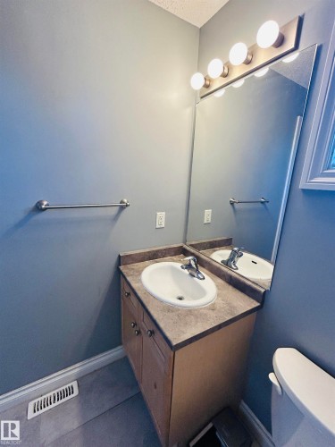 Bathroom vanity with a white oval sink, chrome faucet, and a stone-finish countertop - 89 12050 17 Avenue, Edmonton, AB 