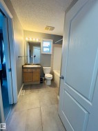 Bathroom featuring large format tile flooring, a wood-finish vanity with countertop sink, and a combination tub and shower - 