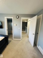 Neutral-toned carpeting extends throughout this interior space, featuring a light gray wall color and white trim - 