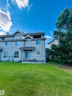 Rear exterior with siding, featuring multiple windows, a sliding glass door, a patio area, and a substantial lawn - 