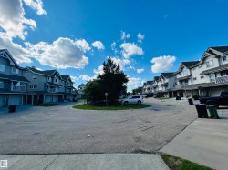 Residential townhome community featuring gray siding, dark roofs, individual balconies, and integrated garage spaces - 