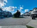 Residential townhome community featuring gray siding, dark roofs, individual balconies, and integrated garage spaces - 89 12050 17 Avenue, Edmonton, AB 