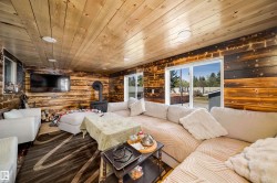 Interior room featuring wood-plank walls and ceiling, a black wood-burning stove, recessed lighting, and large sliding glass doors - 