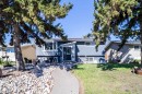 Exterior featuring light blue siding, a dark entry door, and a bay window - 14808 96 Street, Edmonton, AB 