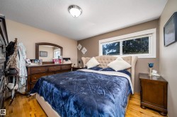 Spacious bedroom with wood-finish flooring, a large window, neutral wall tones, and a flush mount ceiling light - 