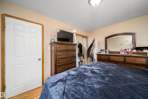 Bedroom featuring wood-finish flooring, a white six-panel door with wood trim, and a ceiling-mounted light fixture - 14808 96 Street, Edmonton, AB 