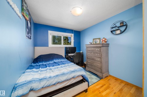Bright interior space featuring light blue walls, wood-finish flooring, and a single window with white trim - 14808 96 Street, Edmonton, AB 