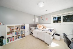 Carpeted bedroom featuring a large window, light gray walls, built-in shelving, and a flush-mount ceiling light - 