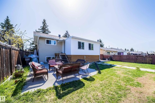 Spacious backyard featuring a concrete patio, expansive lawn, and wooden privacy fencing - 14808 96 Street, Edmonton, AB 