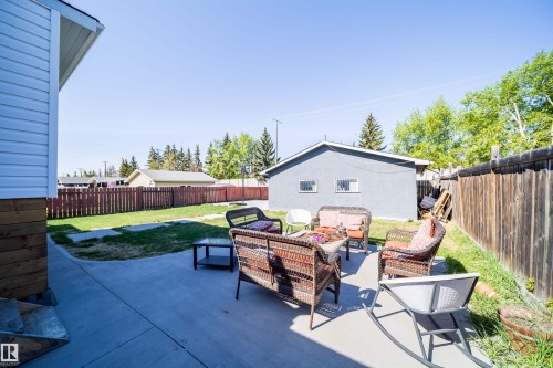 Concrete patio with surrounding lawn area, wood privacy fence, and detached garage structure - 14808 96 Street, Edmonton, AB 