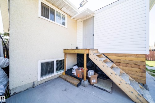 Exterior featuring stucco siding and white vinyl siding, multiple windows, a rear entry door with a small awning, and exterior stairs - 14808 96 Street, Edmonton, AB 