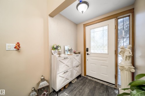 Entryway featuring a white door with a decorative glass insert, a sidelight window, and wood-finish flooring - 14808 96 Street, Edmonton, AB 