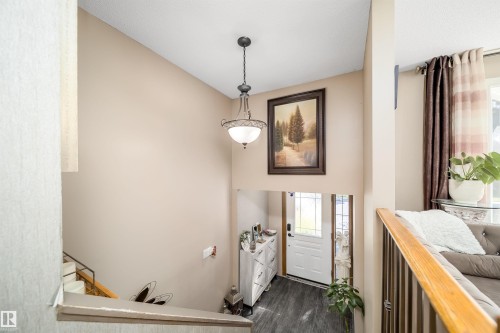 Foyer entrance with a decorative light fixture, high ceilings, wood-finish flooring, and a white front door featuring glass inserts - 14808 96 Street, Edmonton, AB 