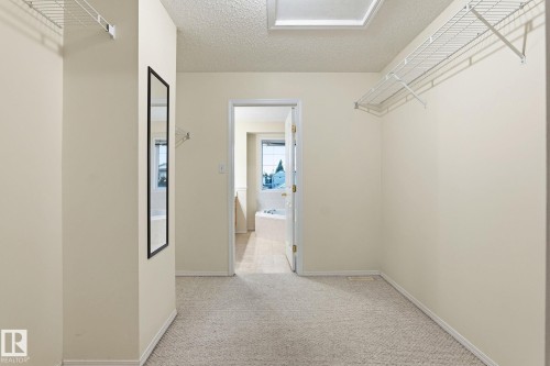 Carpeted walk-in closet with overhead wire shelving and a full-length mirror - 1906 37B Av, Edmonton, AB 